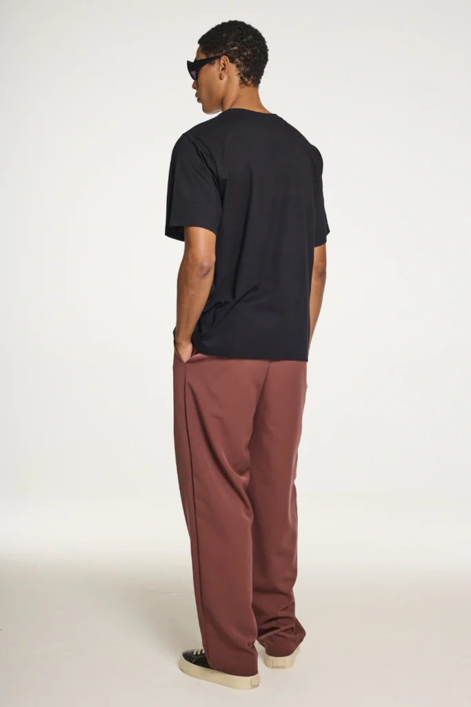 Calça alfaiataria reta marrom com camiseta preta, vista de costas